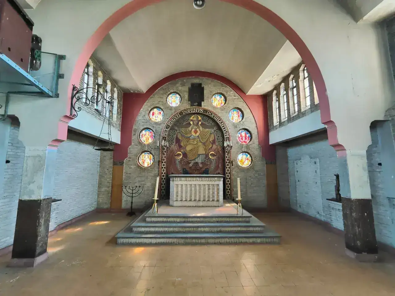 Overzicht van de zaal met gewelfd plafond en glasramen rond de apsis